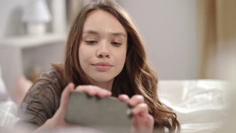 Young-woman-posing-for-mobile-selfie-photo-on-phone-in-bed.-Woman-taking-selfie