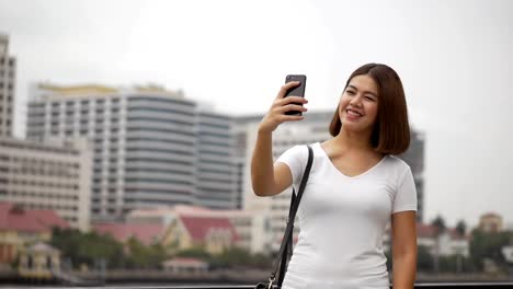 Schöne-junge-asiatische-Frau-mit-Video-Chat-mit-Smartphone-mit-Freunden-in-den-sozialen-Medien-Sommerurlaub.