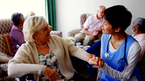 Vista-frontal-del-médico-asiático-que-interactúa-con-la-mujer-mayor-en-el-hogar-de-ancianos-4k