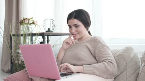 Glückliche-Frau-mit-Laptop-auf-dem-Sofa