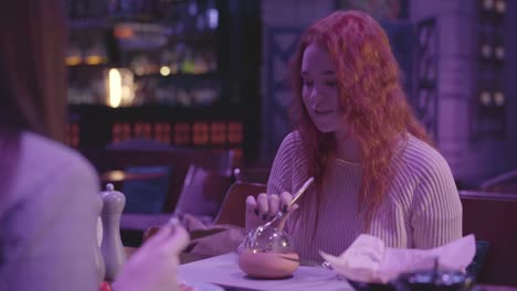 Two-cute-girlfriends-have-dinner-in-a-modern-restaurant-together.