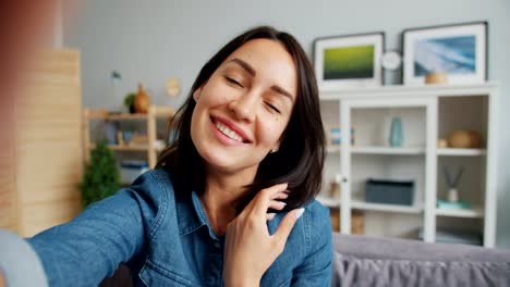 Point-of-view-of-girl-taking-selfie-smiling-posing-looking-at-camera-at-home