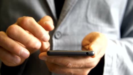 men's-hands-in-a-jacket-work-using-a-touchscreen-smartphone.