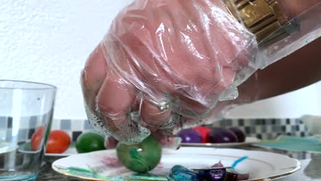 A-woman-in-gloves-paints-eggs