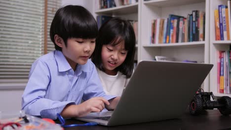 Little-girl-and-boy-using-laptop-to-working-together-at-library.-Education-and-Teachnology-concept.