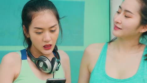 Lifestyle-asiatische-Sportfrauen-halten-Smartphone-spielen-Musik-Entspannung