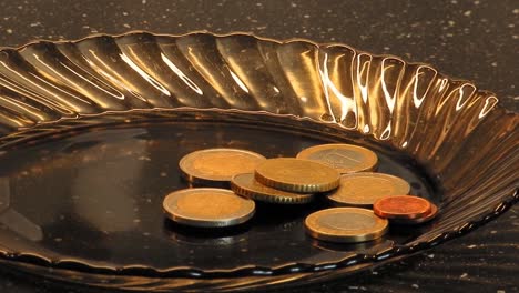 B-roll--footage-of-slowly-zooming-euro-coins-on-a-dark-brown-glass-plate.