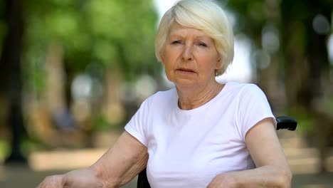 Sad-woman-in-wheelchair-deeply-sighing-sitting-outdoor,-disability,-close-up