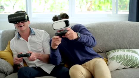 Gay-couple-relaxing-on-couch-playing-virtual-reality-games.-Competing-game.