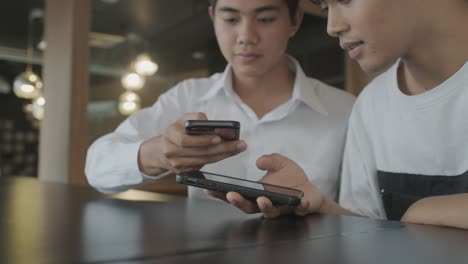 Hombres-jóvenes-que-utilizan-el-teléfono-móvil-para-los-datos-de-transferencia-en-línea.