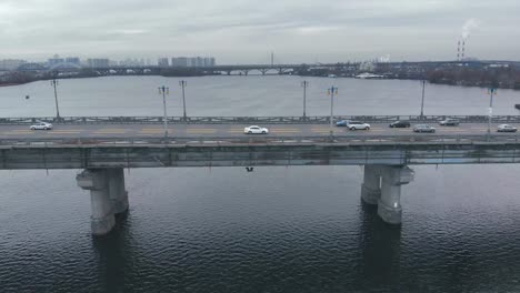 Verkehr-auf-einer-Brücke-über-einen-breiten-Fluss-im-Winter