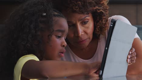 Primer-plano-de-la-abuela-afroamericana-y-nieta-en-casa-usando-tableta-digital-juntos