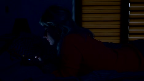 Frau-stehend-auf-dem-Bett-in-ihrem-Schlafzimmer-in-der-Nachtzeit-und-Scrollen-auf-ihrem-Smartphone