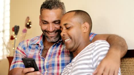 Happy-Gay-Couple-Looking-At-Pictures-On-Mobile-Phone