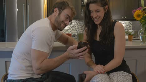 Attractive-couple-looking-at-the-same-smart-phone-together-laughing-and-smiling