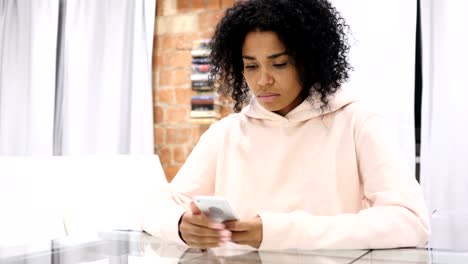 Afro-amerikanische-Frau-bei-der-Arbeit-Surfen-Smartphone-im-Büro