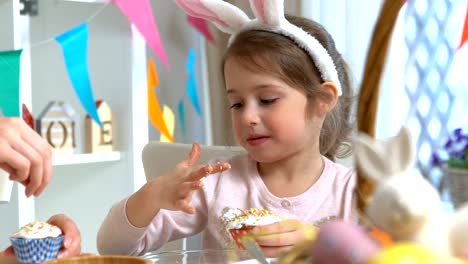 Joven-madre-y-su-hija-con-orejas-de-conejo-cocinar-cupcakes-de-Pascua