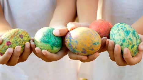 Close-up-of-two-children-hand-holding-a-easter-eggs-in-sunshine-background