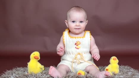 Cute-little-toddler-baby-boy,-playing-with-colorful-easter-eggs-and-little-decorative-ducks,-isolated-shot,-beige-background