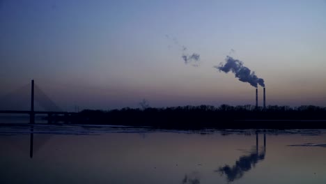 The-smoky-plant-on-the-background-of-the-river-and-the-setting-sun