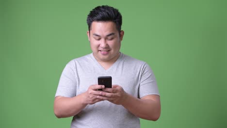 Young-handsome-overweight-Asian-man-against-green-background