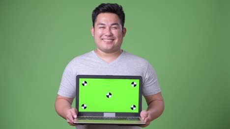 Young-handsome-overweight-Asian-man-against-green-background