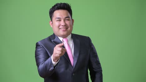 Joven-guapo-empresario-asiático-con-sobrepeso-sobre-fondo-verde