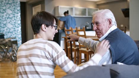 Young-Woman-Ironing-Shirt-for-Elderly-Man-in-Wheelchair