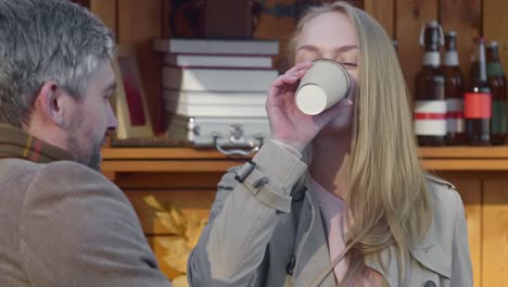 Young-woman-drinking-coffee-with-a-man-near--food-booth