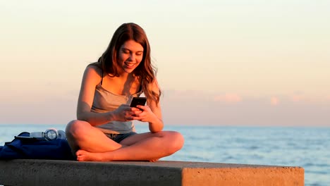 Teenager-Studentin-SMS-bei-Sonnenuntergang-am-Strand