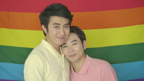 Portrait-of-young-asian-gay-couple-posing-in-front-of-gay-pride-rainbow-flag.