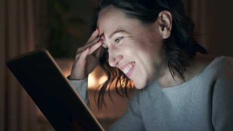 Cheerful-woman-using-digital-tablet-at-night