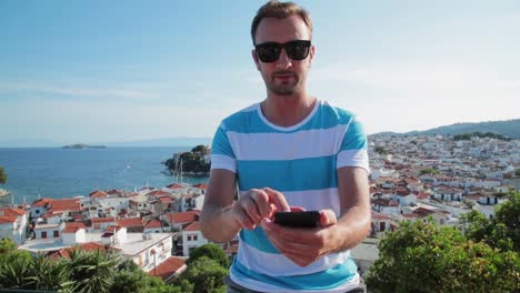 Man-using-cellphone-on-the-ocean-/-sea-small-town-coast.