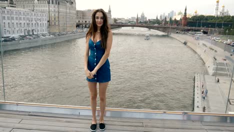 Brunette-Frau-Modell-stand-Bridge-River-mit-Blick-auf-Kamera-und-süßes-Lächeln-4k.