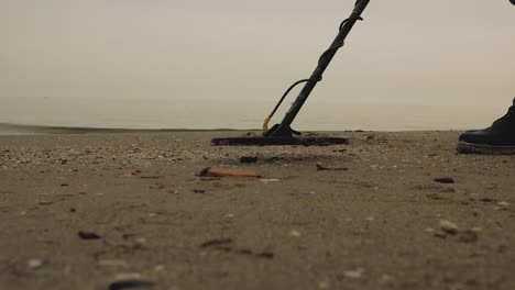 Mann-am-Meer-mit-einem-Metalldetektor-sucht-Schatz-im-Sand