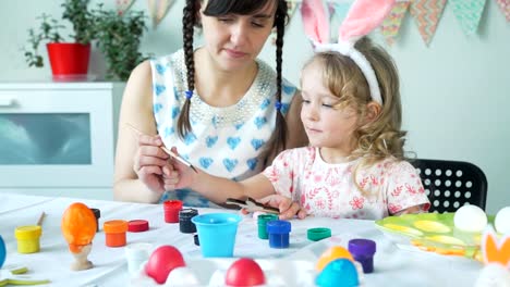 Madre-ayudando-hija-a-pintar-conejito-de-Pascua