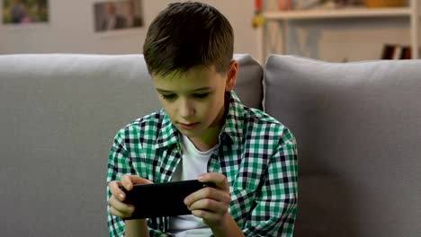 Boy-jugando-videojuego-en-el-teléfono-inteligente-en-casa,-adicción-gadget-en-la-edad-temprana