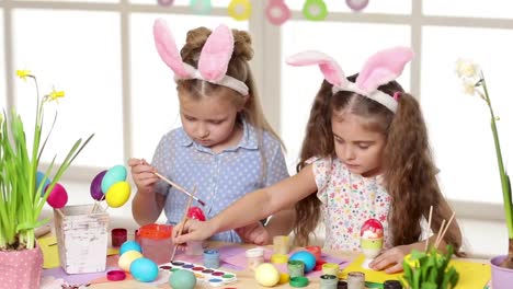 Happy-children-wearing-bunny-ears-painting-eggs-on-Easter-day.