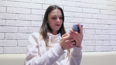 Woman-is-typing-a-message-on-mobile-phone-sitting-and-waiting-somebody-in-cafe.