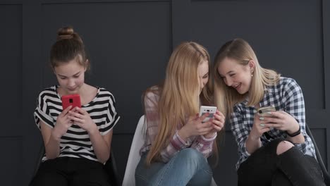 Chicas-adolescentes-divirtiéndose-mientras-que-los-mensajes-de-texto-en-los-teléfonos-móviles