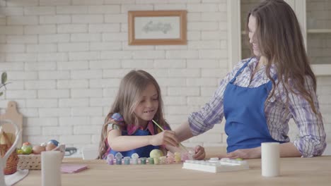 Mama-und-niedliche-kleine-Tochter-Färbung-Ostereier-mit-Farben-und-Pinsel.