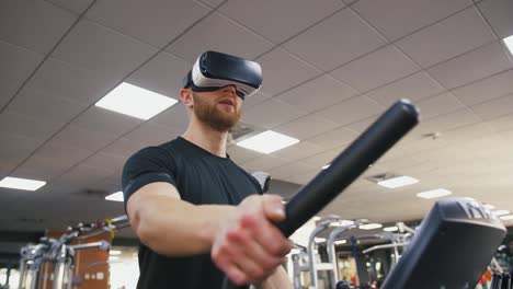 Joven-fuerte-haciendo-ejercicio-en-la-cinta-en-el-gimnasio,-usando-gafas-VR,-cámara-lenta