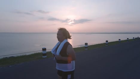 Las-mujeres-asiáticas-que-trotar-en-la-calle-en-la-luz-del-sol-temprano-en-la-mañana-en-el-almacenamiento-de-agua-PA-Sak-Jolasid-Dam.-concepto-de-perder-peso-con-ejercicio-para-la-salud.-Cámara-lenta