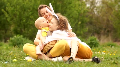 Schöne-Familie-umarmt-im-Park-bei-einem-Picknick.-Fröhliche-Osterfamilie.-Mama-und-zwei-Söhne.-Muttertag