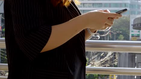 Close-up-hand-young-asian-woman-walking-texting-with-friend-on-smartphone-at-urban-city-background,-Searching-for-social-media