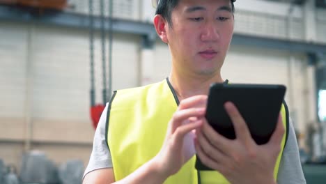 Young-Asian-male-factory-worker-using-a-digital-tablet