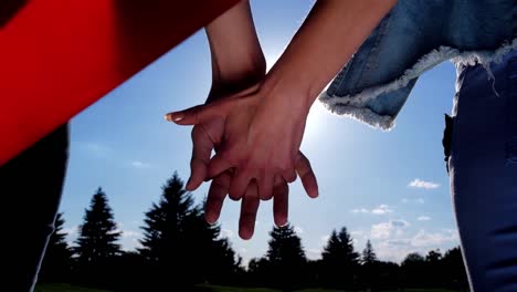 Lesbian-couple-joining-hands-looking-at-bright-sun