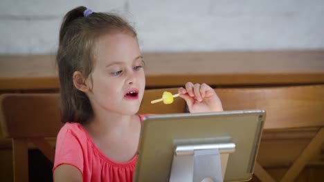 hermosa-niña-comiendo-helado-y-viendo-la-caricatura-en-la-tableta