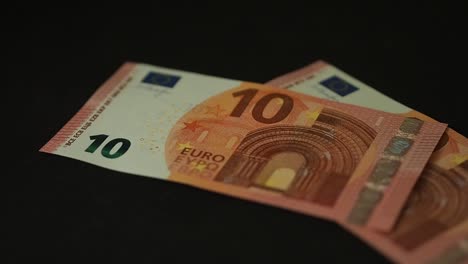 Banknotes-10-euro-slowly-falling-on-the-black-table.-Closeup.-Slow-motion