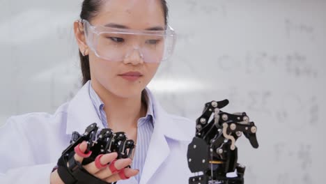 Asiatische-Frau-testet-Cyborg-Hand-im-Labor.